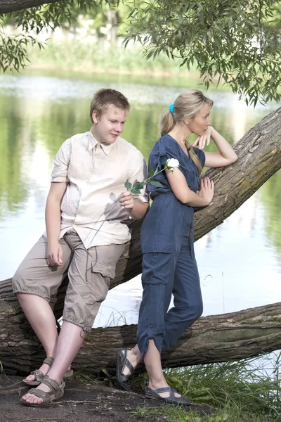 Young guy and girl on the nature near lake, reconciliation after quarrel — Stock Photo, Image