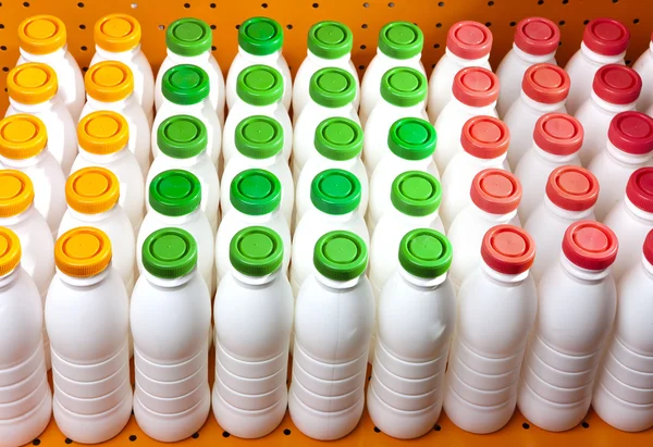 Dairy products bottles with bright covers on a shelf in the shop — Stock Photo, Image