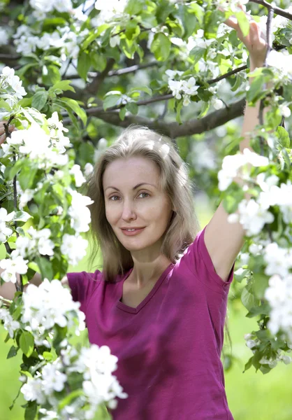 Junge attraktive Frau am blühenden Apfelbaum — Stockfoto