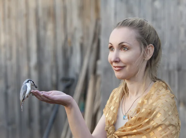 De jonge mooie vrouw een vogel-feeds van een hand — Stockfoto