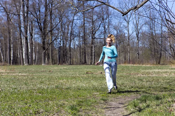 A nő fut a pályán, a tavaszi fa — Stock Fotó