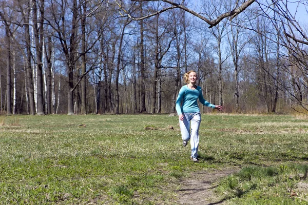Женщина бежит по трассе в весеннем лесу — стоковое фото