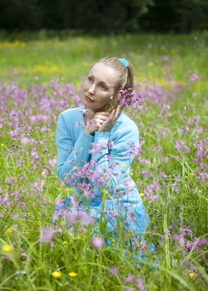 The beautiful young woman in a blue dress in the field — Stock Photo, Image
