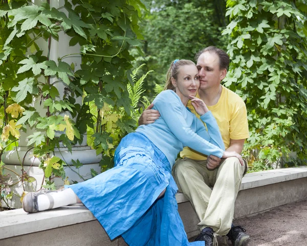 Unga lyckliga paret sitter i de arbour tvinnat gröna — Stockfoto