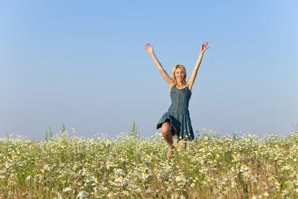 Щаслива молода жінка стрибає в поле ромашок — стокове фото
