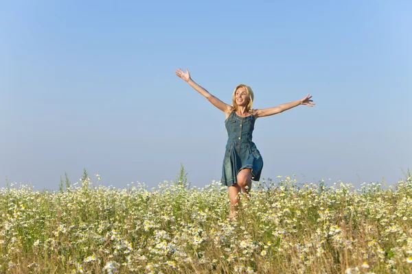 La joven feliz salta en el campo de las manzanillas — Foto de Stock