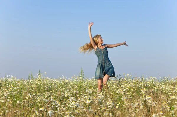 The happy young woman jumps in the field  of camomiles — Stock Photo, Image