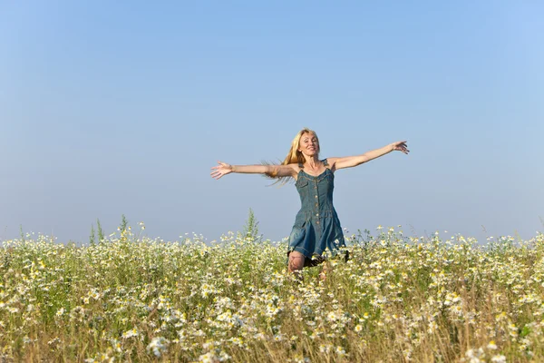 The happy young woman jumps in the field  of camomiles — Stock Photo, Image