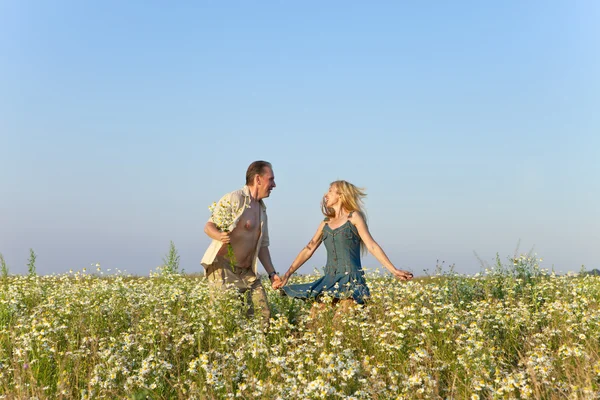 The happy young pair in the field of chamomiles jumps — Stock Photo, Image