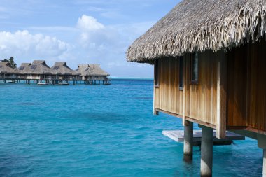 Tipik Polinezya manzarası - su üzerindeki küçük evler.
