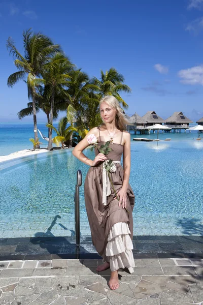 La mujer en un vestido largo antes de la piscina infiniti, con vistas al mar —  Fotos de Stock