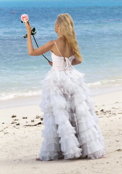 La mujer joven hermosa en el vestido de la novia sobre la arena al borde del mar —  Fotos de Stock