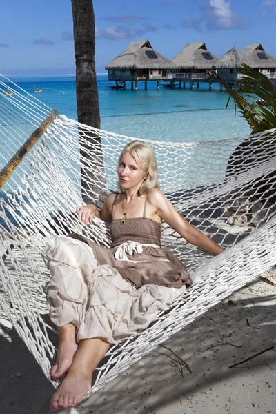 La bella donna in un prendisole lungo in un'amaca su uno sfondo marino — Foto Stock