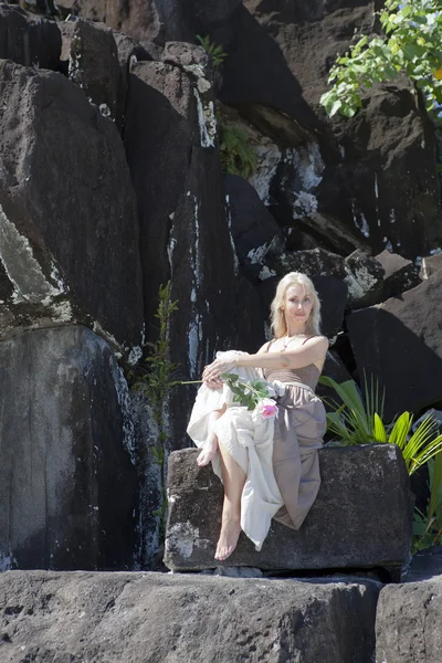 Žena v dlouhých šatech na černých kamenů. Polynésie — Stock fotografie