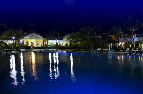Edifícios com iluminação noturna atrás da piscina — Fotografia de Stock