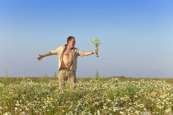 El joven feliz en el campo con un ramo de manzanillas —  Fotos de Stock