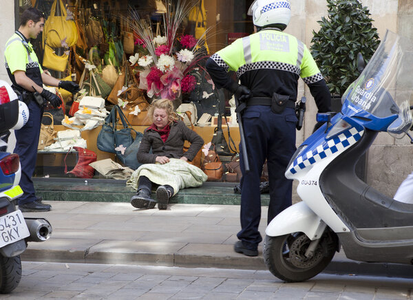 Police officers talk with homeless, sitting at a show window of boutique 10 May 2010 in Barcelona, Spain