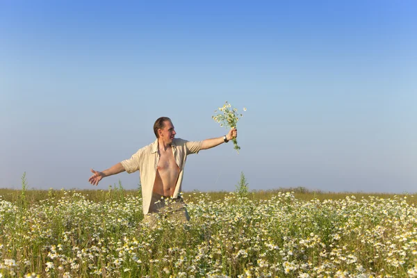 カモミールの花束とフィールドで幸せな若い男 — ストック写真