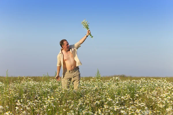 Щасливий молодий чоловік в полі з букетом ромашок — стокове фото