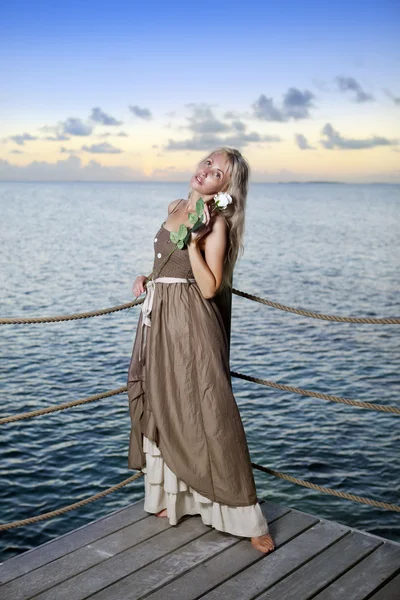 La hermosa mujer en un vestido largo en una plataforma de madera sobre el mar — Foto de Stock