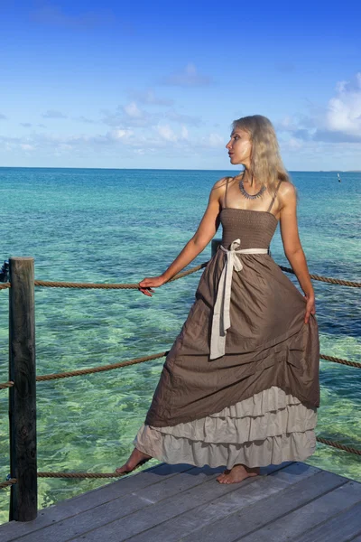 Krásná žena v dlouhých šatech na dřevěné plošině nad mořem — Stock fotografie