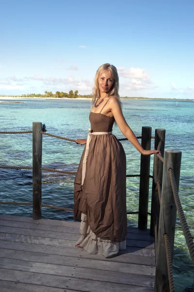 La hermosa mujer en un vestido largo en una plataforma de madera sobre el mar —  Fotos de Stock