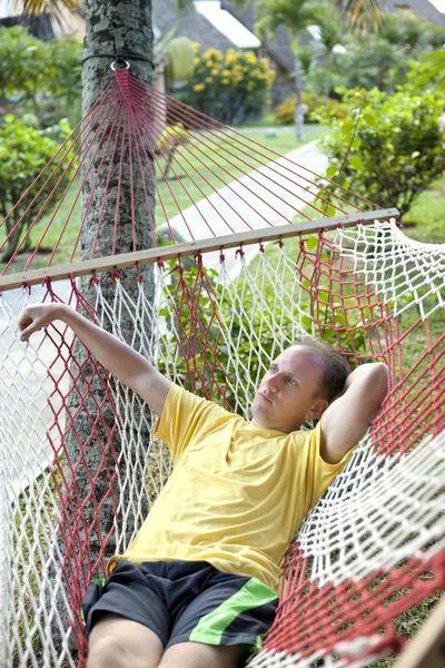 El hombre descansa en una hamaca en un entorno de la naturaleza tropical —  Fotos de Stock