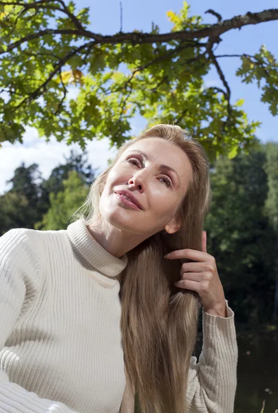 Beautiful woman combs long hair in the summer day on the river bank — Stock Photo, Image