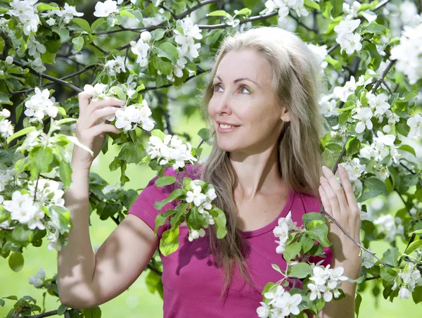 Giovane donna attraente in piedi vicino al melo in fiore — Foto Stock