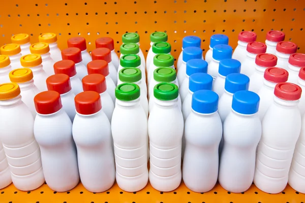 Dairy products bottles with bright covers on a shelf in the shop — Stock Photo, Image