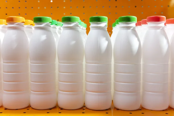 Dairy products bottles with bright covers on a shelf in the shop — Stock Photo, Image