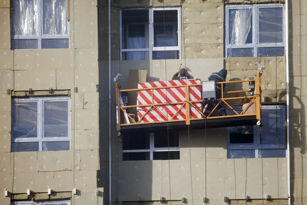 Bau des Gebäudes. Arbeiter wärmen Außenwände. — Stockfoto