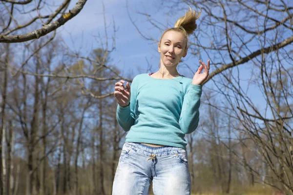 The happy young woman in bright clothes jumps in spring park — Stock Photo, Image
