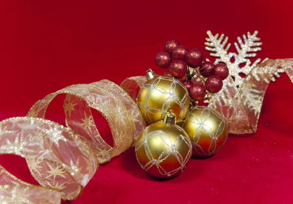 Bolas de Ano Novo dourado e fita em um fundo vermelho — Fotografia de Stock