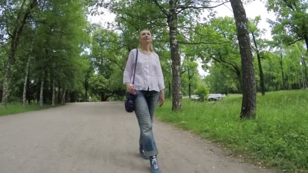 A mulher bonita vai a caminho no parque verde. Movimento lento — Vídeo de Stock