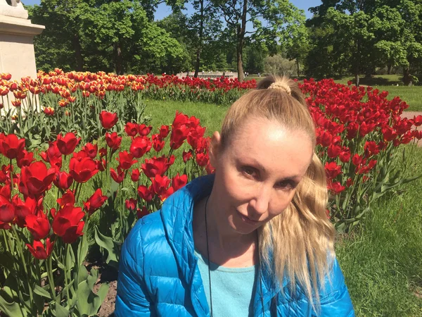 Die junge Frau sitzt neben den leuchtend blühenden Tulpen — Stockfoto