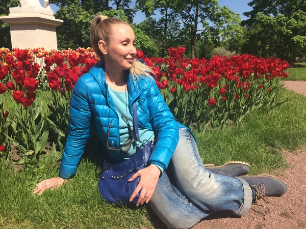 La joven se sienta cerca de los tulipanes florecientes — Foto de Stock