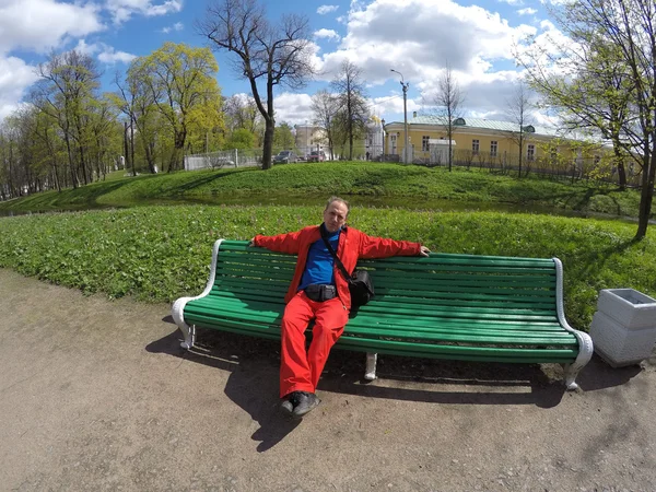 Muž v obleku sportovní červená na lavičce v parku na jaře — Stock fotografie