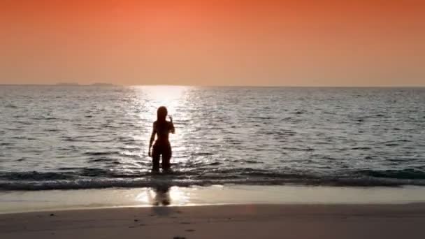 Silhueta da mulher contra um pôr-do-sol no oceano — Vídeo de Stock