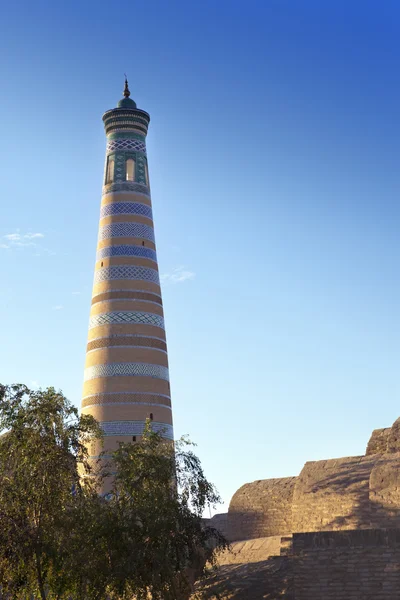 Antiguo minarete en la calle de la ciudad vieja. Uzbekistán. Khiva. — Foto de Stock