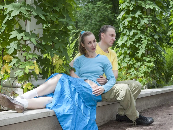 Glücklicher Mann und Frau sitzen im Sommer auf einer Bank im Park — Stockfoto