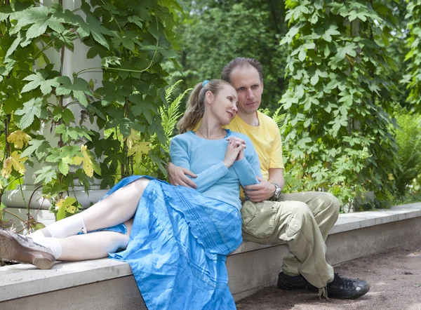 Feliz hombre y la mujer se sientan en un banco en el parque en el verano —  Fotos de Stock