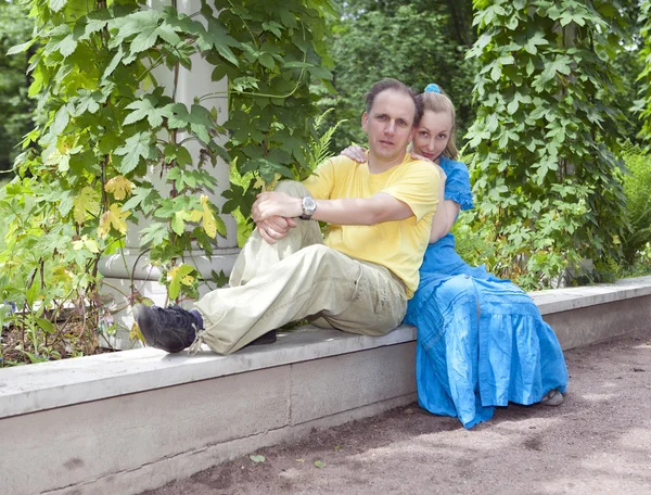 Happy man and the woman sit on a bench in park in the summer — Stock Photo, Image