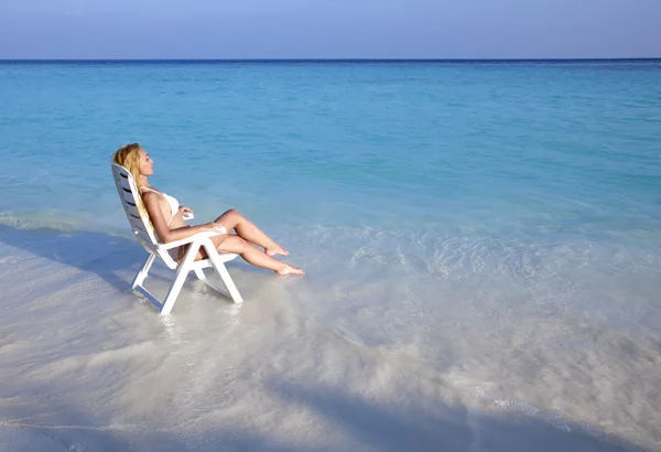 Jovem mulher bonita bronzeados em cadeira de praia no mar — Fotografia de Stock