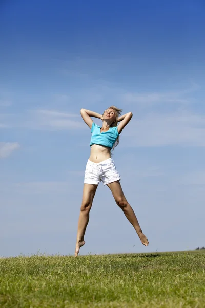 La femme heureuse saute dans un champ vert d'été — Photo