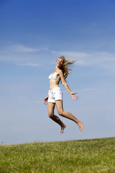 Szczęśliwa kobieta wskakuje w lato zielone pole — Zdjęcie stockowe