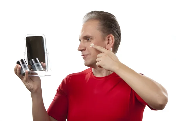 The mature man applies the cream which is looking after face skin — Stock Photo, Image