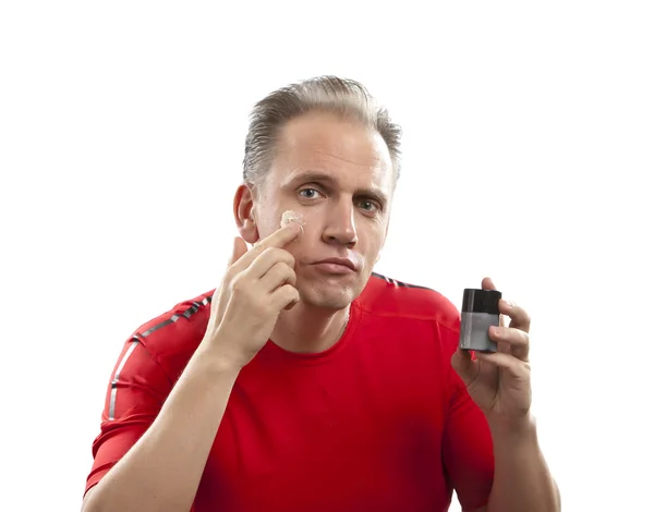 Confused man before a mirror the first time tries a man's against wrinkles cream — Stock Photo, Image