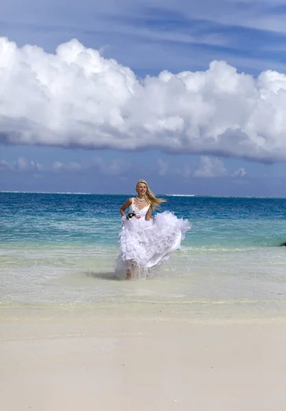 Mooie vrouw in een bruiloft jurk loopt op golven van de zee — Stockfoto