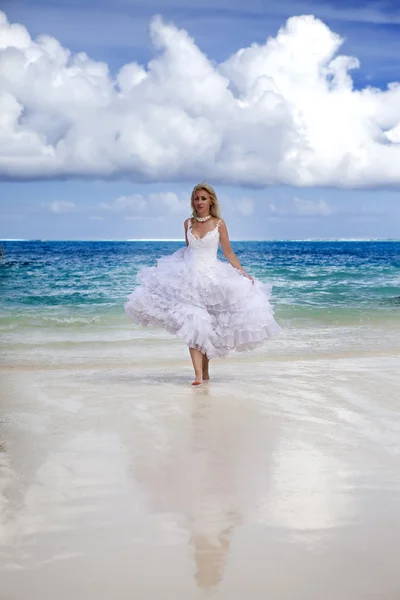 Bella donna in un abito da sposa corre sulle onde del mare — Foto Stock